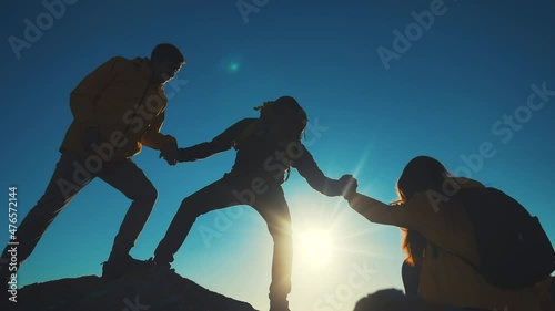 help team concept. team silhouette of climber stretching a helping hand to a friend. business teamwork success concept. silhouette business travel three tourists pull sunlight a helping hand photo