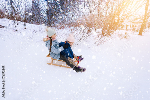 Two children ride on wooden retro sled on sunny winter day. Active winter outdoors games. Winter activities for kids. Children playing with snow in park. Happy Christmas vacation concept