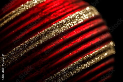 Tree decorations in red and gold. Close up of a red patterned Christmas bauble with glitter stripes.