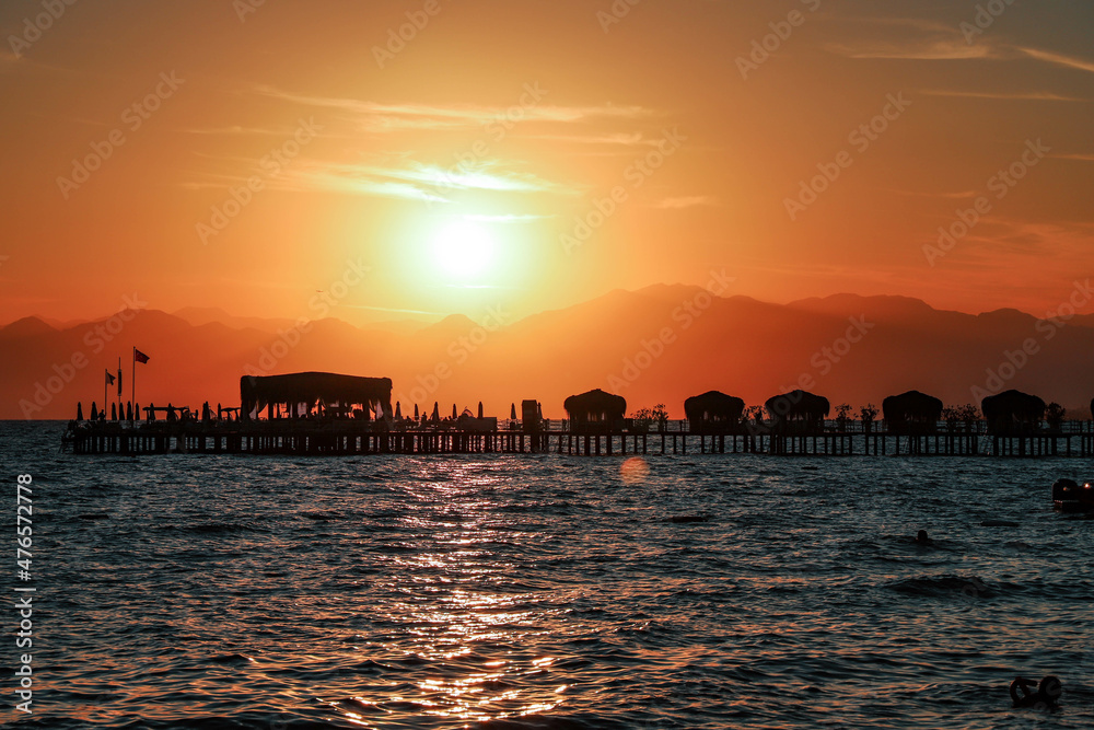 Sunset on the beach with dark buildings and mountains around. Sunset over the sea. Vacation background