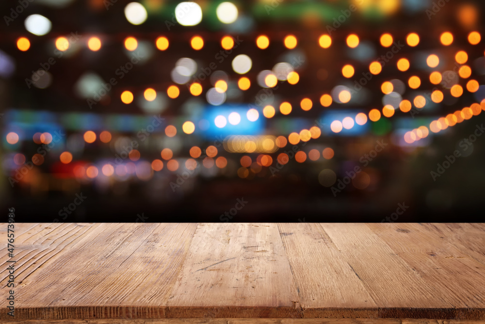 background Image of wooden table in front of abstract blurred restaurant lights