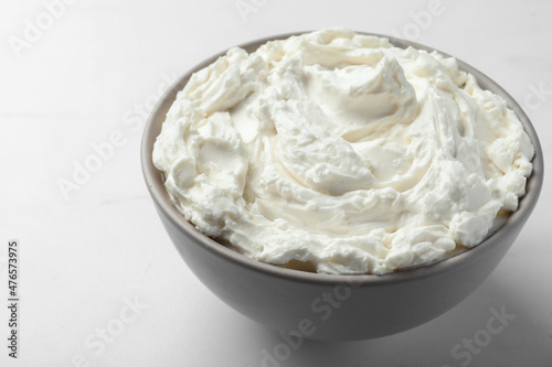 Bowl of tasty cream cheese on white table, closeup