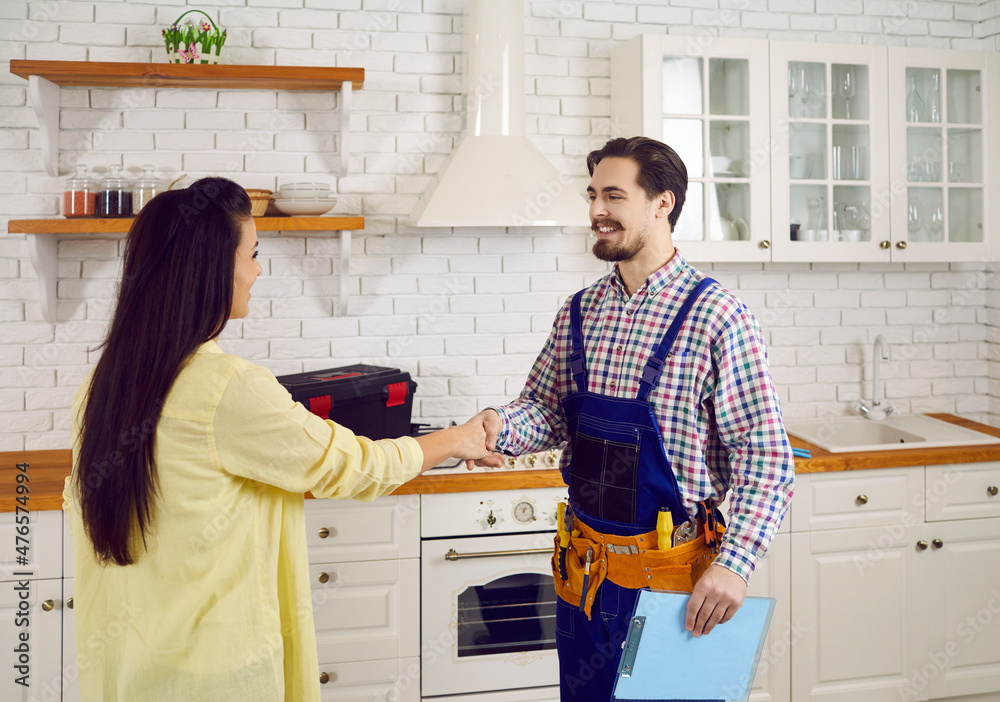 Plumber or repairman in blue overalls with tool belt holding clipboard with contract and shaking