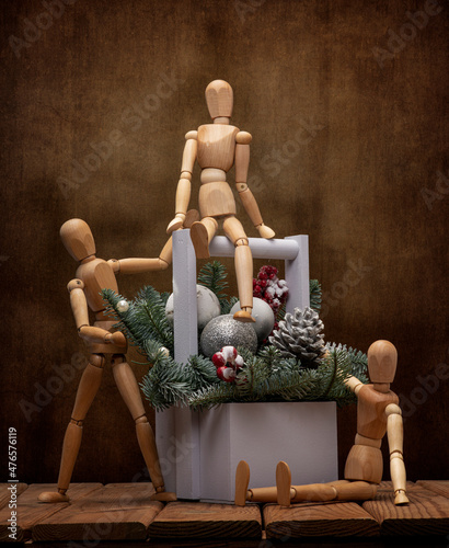 Wooden men celebrate the New Year in a cheerful company with Christmas toys and a Christmas tree on a wooden table and an artistic background. photo