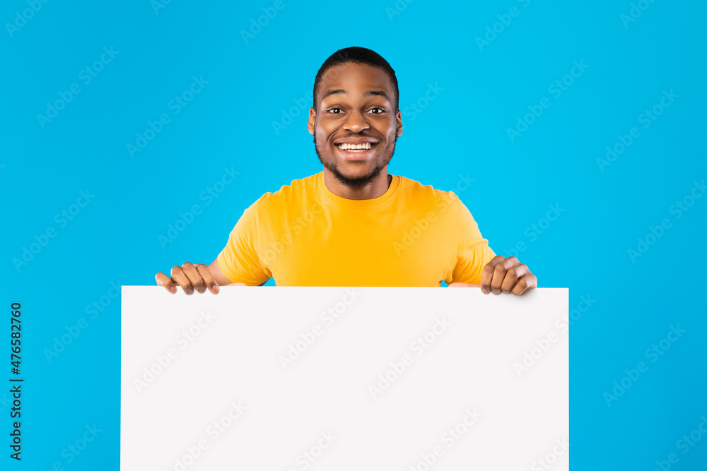 Black Guy Holding Empty White Paper Board Over Blue Background Black Guy Holding Empty White Paper Board Over Blue Background