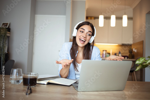 Teenage smiling girl using a laptop and wearing headphones © Dragana Gordic