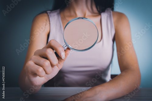 young woman holding a magnifying glass by the table