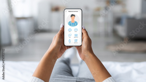 Принти на полотні Woman laying on bed with mobile phone, using medical app
