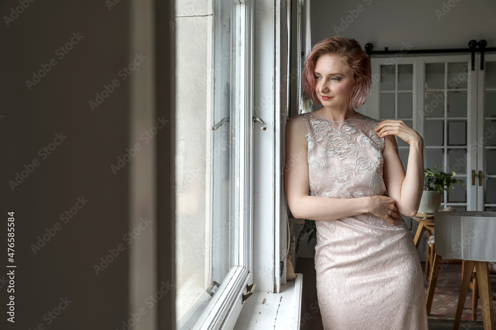 Young woman in dress looking out the window Young woman in dress looking out the window