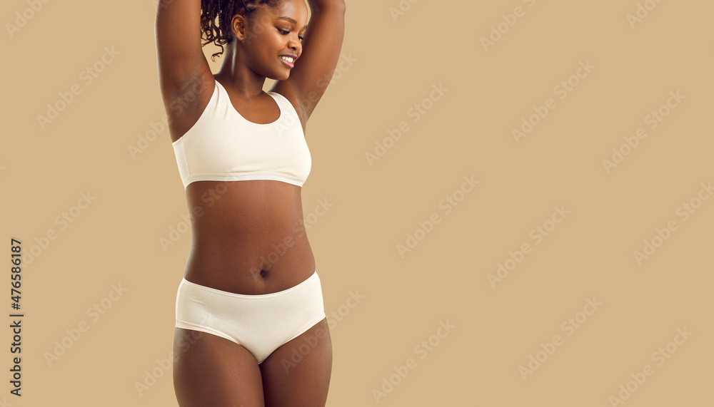 Portrait of beautiful young African American woman in underwear lying  relaxing on white bed at home. Smiling pretty millennial black female in  underclothing garment. Body positive concept. Stock-foto