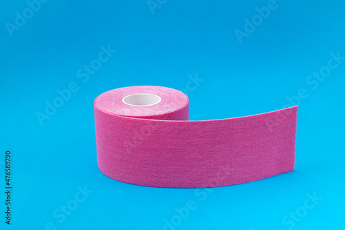 Closeup of roll of pink kinesio tape on the blue surface photo