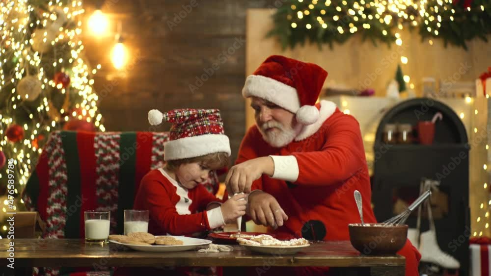 Santa and child in santa hat decorating Christmas gingerbread cookies in retro kitchen at home. Cooking traditional festive sweets. Home bakery, food, Christmas tree and happy New year kids concept. Santa and child in santa hat decorating Christmas gingerbread cookies in retro kitchen at home. Cooking traditional festive sweets. Home bakery, food, Christmas tree and happy New year kids concept.