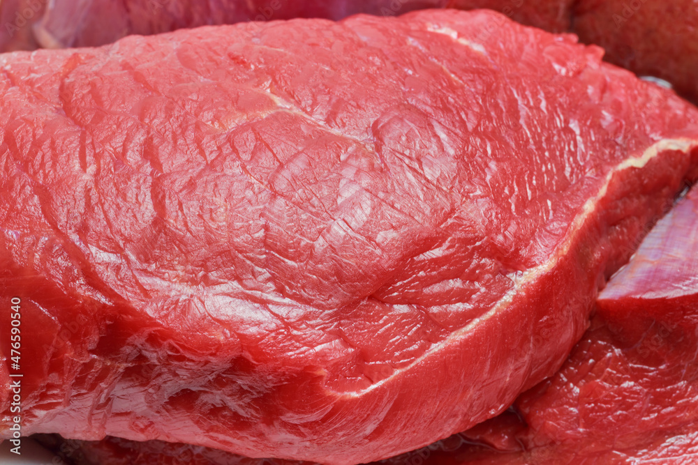 A piece of raw red meat beef fillet close-up. Food background. Source of vitamins B, A, amino acids, protein, collagen, choline A piece of raw red meat beef fillet close-up. Food background. Source of vitamins B, A, amino acids, protein, collagen, choline