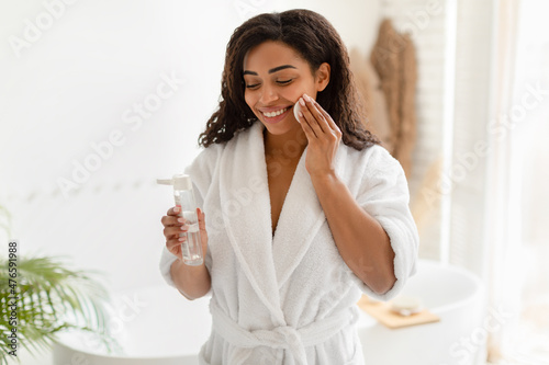 Black Female Using Cotton Pad And Micellar Water In Bathroom