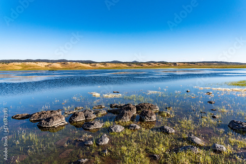 Lake Afnourir in Morocco. Grass and flowers grow in the water of the lake among the rocks that line the shore