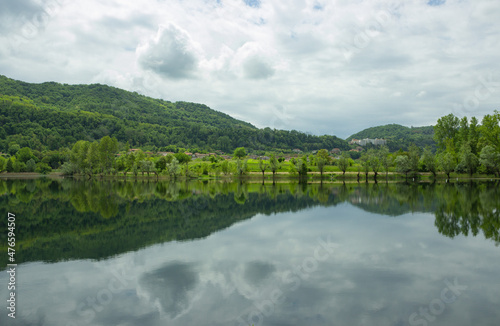 Hilly landscape. View of the lake with reflection of the mountains and clouds.