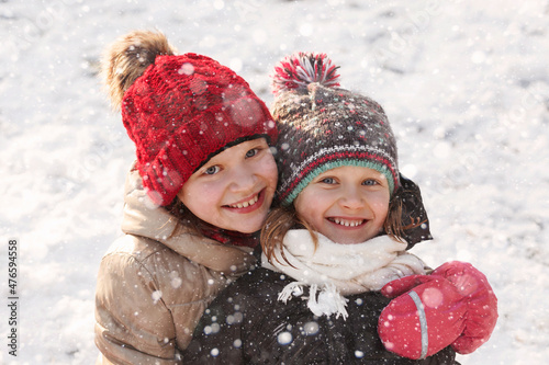 Happy hugging girls kids in snow winter. Winter smiling children walking playing with snow. Winter holidays