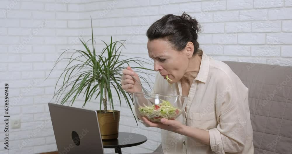 Snack during working hours. A woman at remote work at home eats salad and works on the computer. Snack during working hours. A woman at remote work at home eats salad and works on the computer.