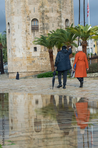 Sevilla, España - 22 de diciembre de 2021: Pareja paseando por el paseo de Colon, junto a la torre del oro, un día de intensa lluvia en la ciudad photo