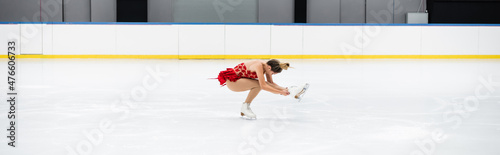Bilde på lerret full length of young woman in dress performing sit spin in professional ice aren