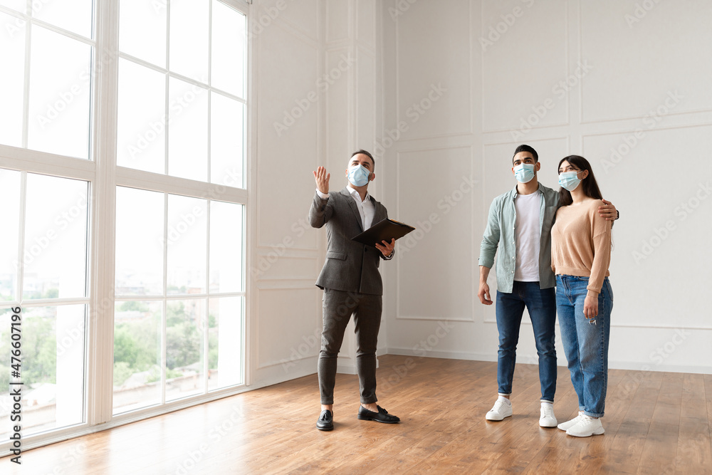 Estate Agent In Medical Mask Showing Buyers New Apartment