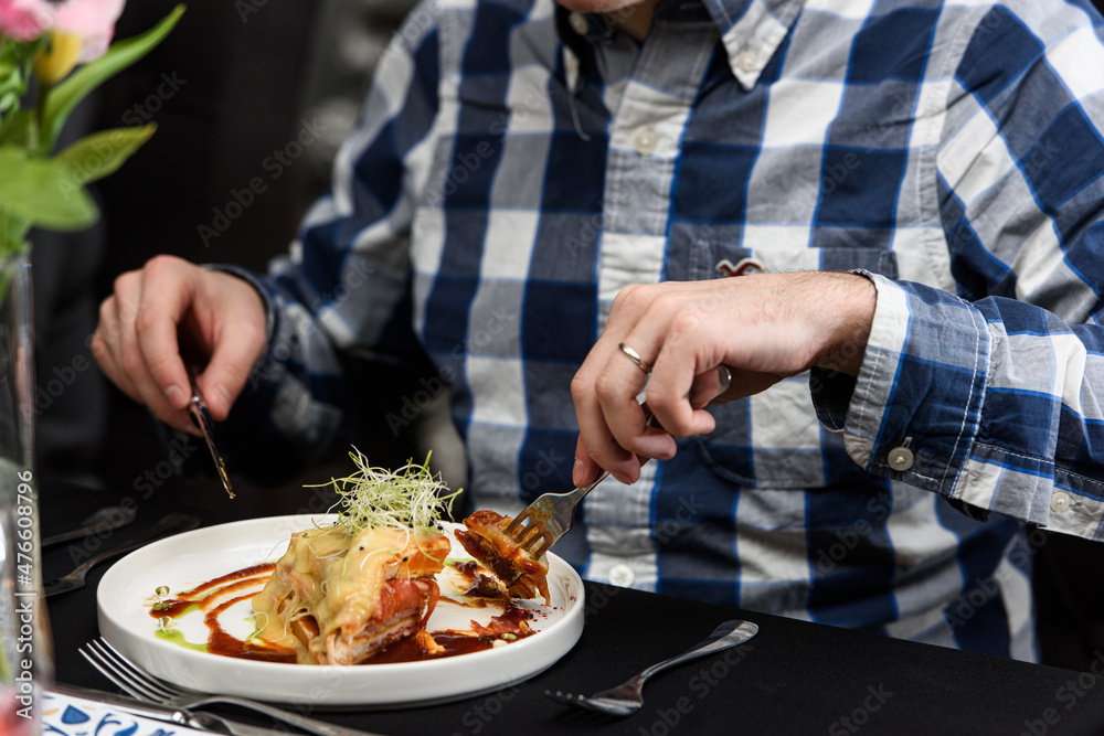 Man eating Francesinha, traditional Portuguese sandwich in a restaurant. National cuisine concept