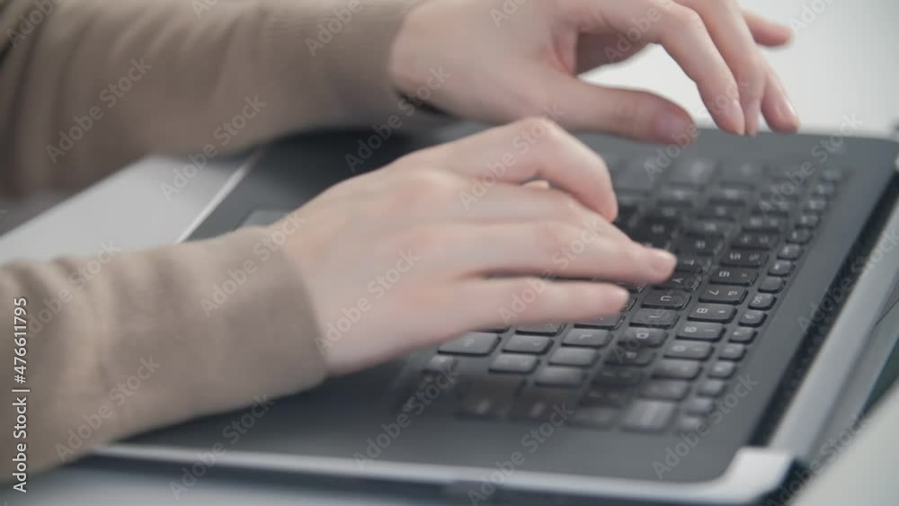Freelancer writer typing text on laptop keyboard while working from home on lockdown. Woman working on notebook computer behind white table in office Freelancer writer typing text on laptop keyboard while working from home on lockdown. Woman working on notebook computer behind white table in office