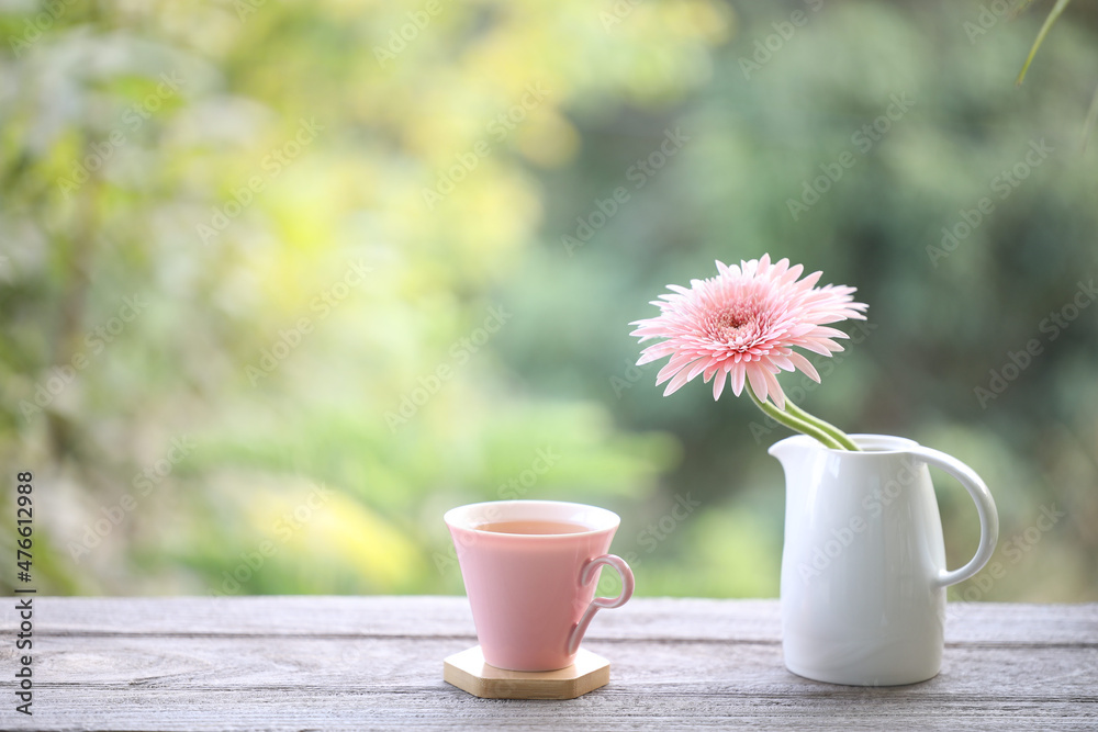 Pink cup and pink gerbera flower on wooden table