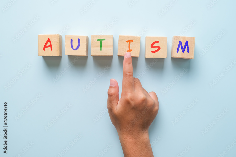 Children hand and autism on wooden squares blue background top view Children hand and autism on wooden squares blue background top view