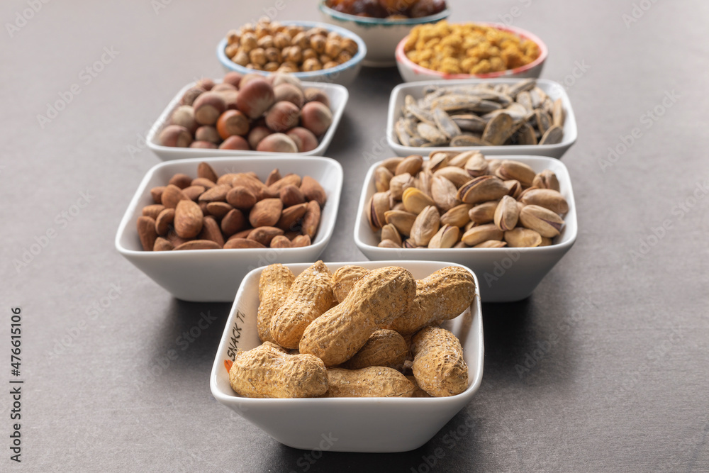 Peanuts in shell in selective focus. Background of dried mulberry, hazelnut, pistachio, grape, almond, yellow chickpea and sunflower seeds. Peanuts in shell in selective focus. Background of dried mulberry, hazelnut, pistachio, grape, almond, yellow chickpea and sunflower seeds.