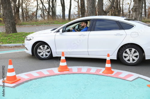 Young man in car on test track with traffic cones. Driving school