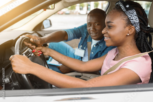 Happy african american woman attending driving school, driving with coach