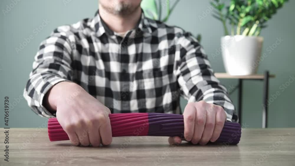 A man doing wrist exercises with theraband flexbar to eliminate joint pain in hand, arm and