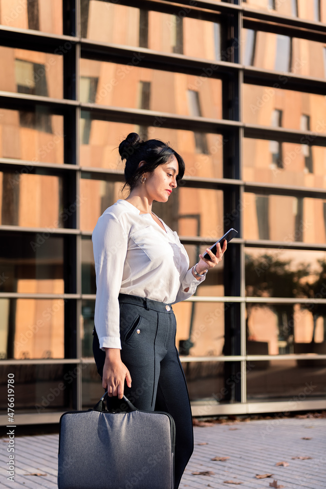 woman checking phone in front of office building