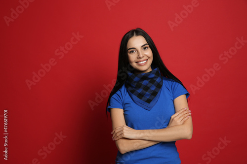 Young woman wearing stylish bandana on red background, space for text