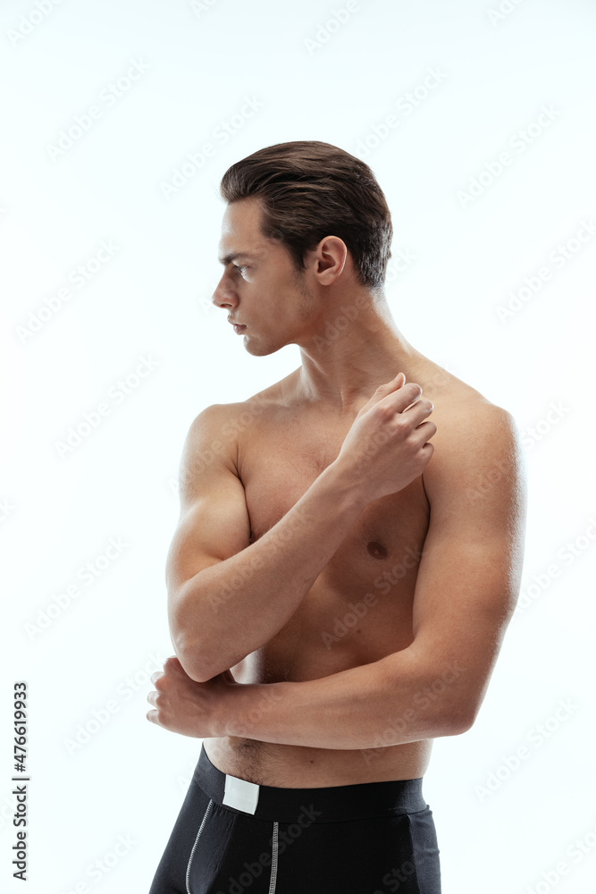Fototapeta premium Half-length portrait of young handsome shirtless sportive man wearing black boxer-briefs standing isolated on white background.