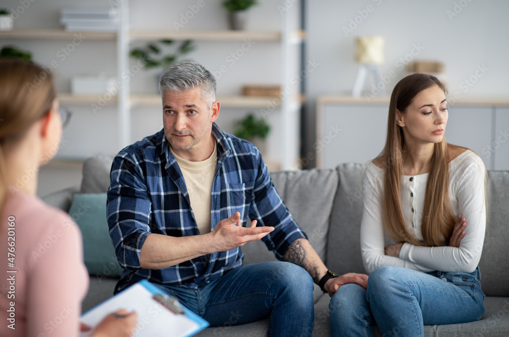 Unhappy mature couple having meeting with marital counselor, discussing relationship problems