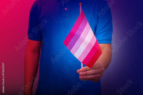 Hand holding flag in lesbian pride colors. © Marcela Ruty Romero