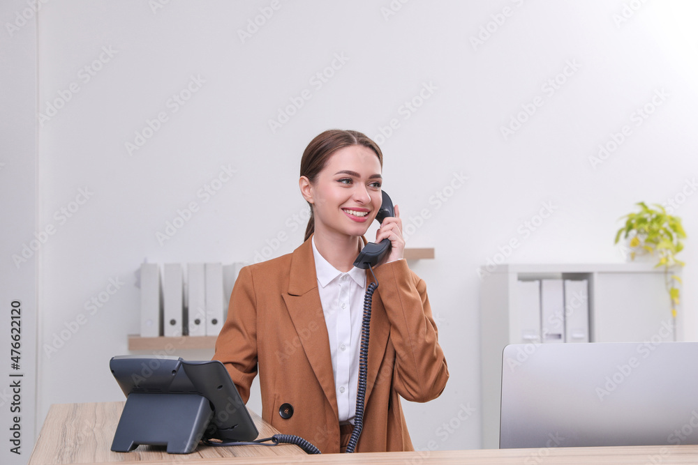 Female receptionist talking on phone at workplace