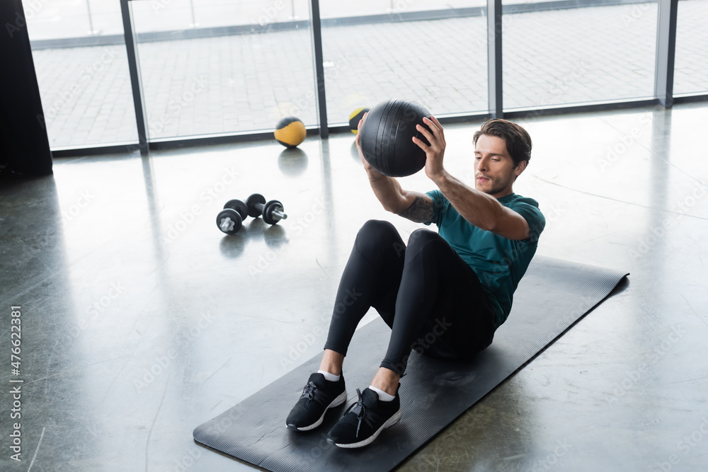 Fototapeta premium Sportsman working out with slam ball on fitness mat in sports center