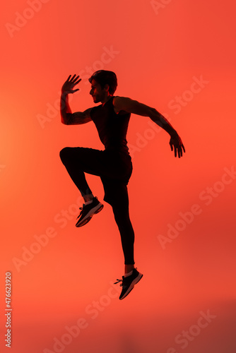 Side view of sportsman jumping on red background