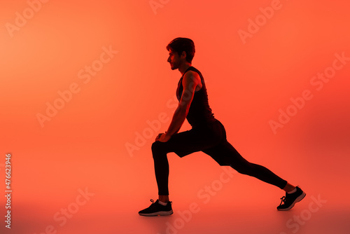 Side view of athletic sportsman training on red background