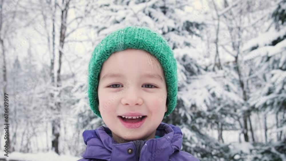 Winter portrait of happy cheerful little child boy smiling looking at camera standing near snow covered trees outdoor. Happy 5 years kid joy emotion in snowfall. Positive and happiness concept. Winter portrait of happy cheerful little child boy smiling looking at camera standing near snow covered trees outdoor. Happy 5 years kid joy emotion in snowfall. Positive and happiness concept.