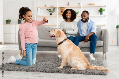 Happy black girl giving a treat to her labrador