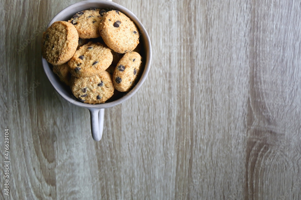 Ceramic bowl filled with chocolate chip cookies on wooden table. Flat lay. Ceramic bowl filled with chocolate chip cookies on wooden table. Flat lay.