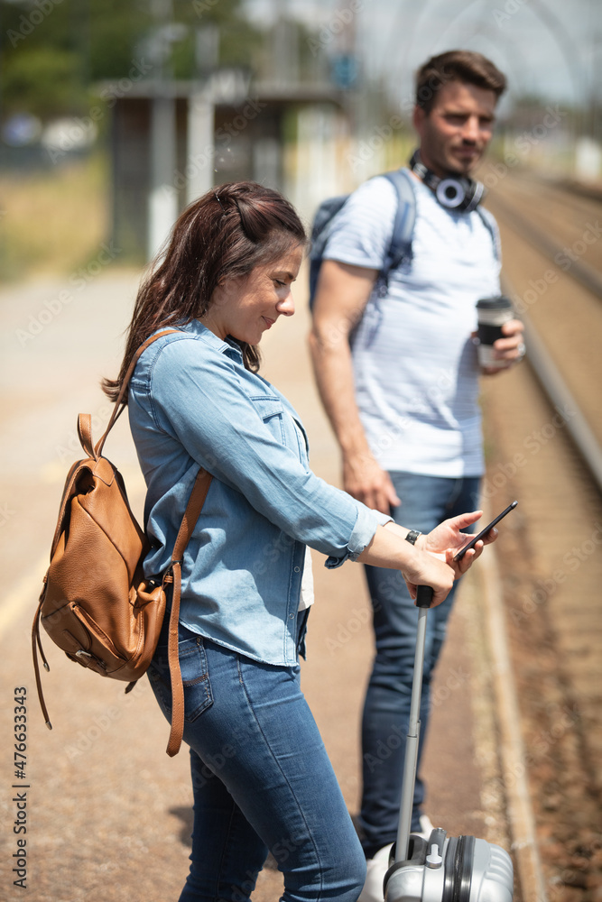 couple waiting on the platform woman using a smartphone couple waiting on the platform woman using a smartphone