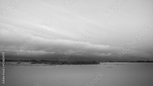beautiful dramatic cloud coming up over snow covered field, black and white