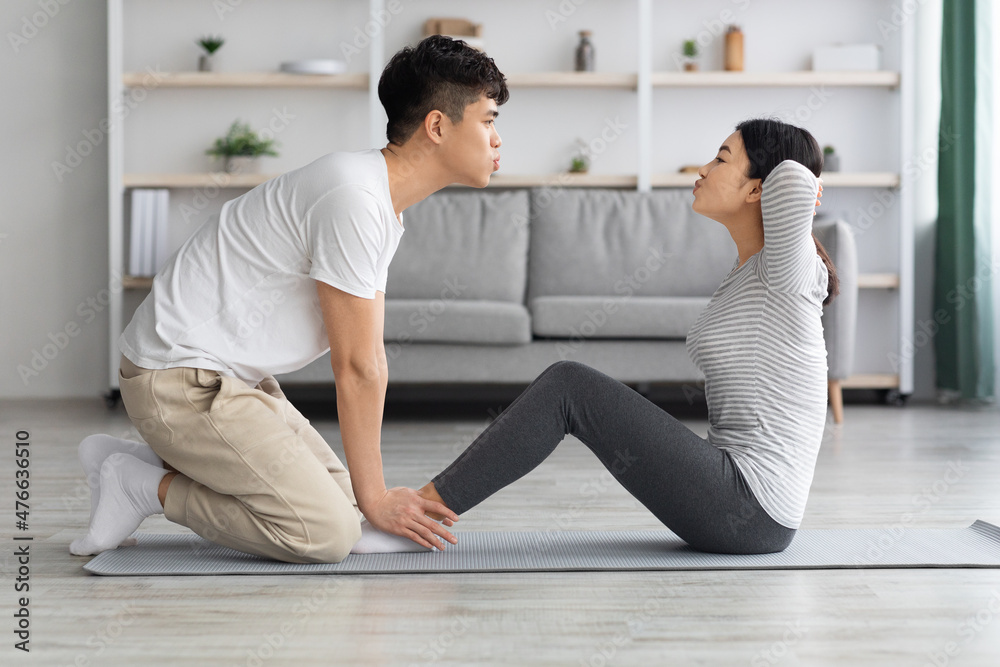 Motivated asian man and woman working on abs at home Motivated asian man and woman working on abs at home