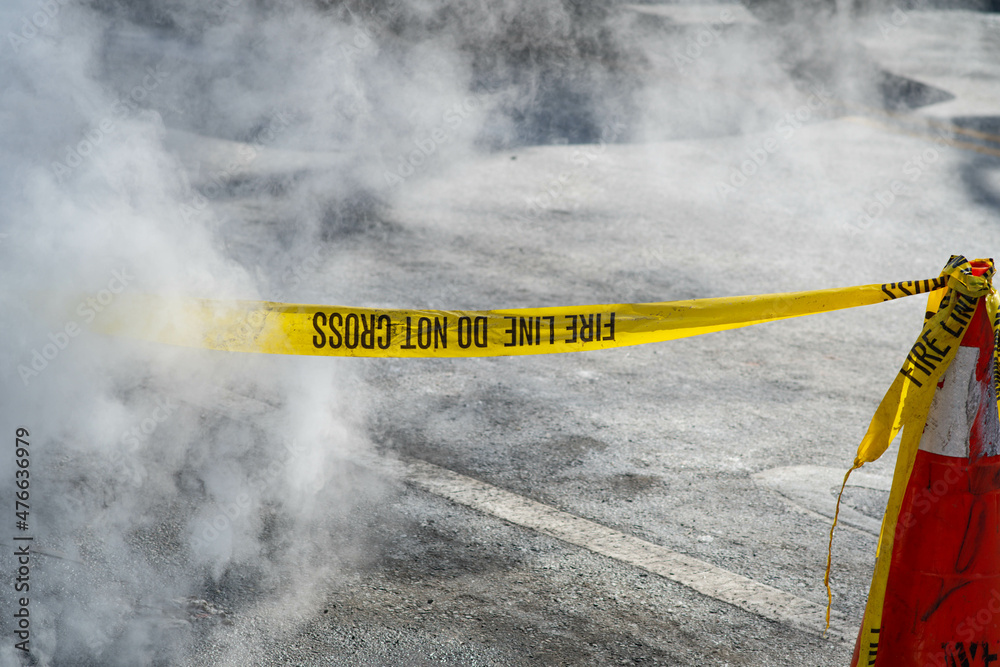 Caution tape on the ground in a city street environment with smoke
