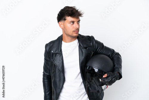 Young caucasian man with a motorcycle helmet isolated on white background looking to the side